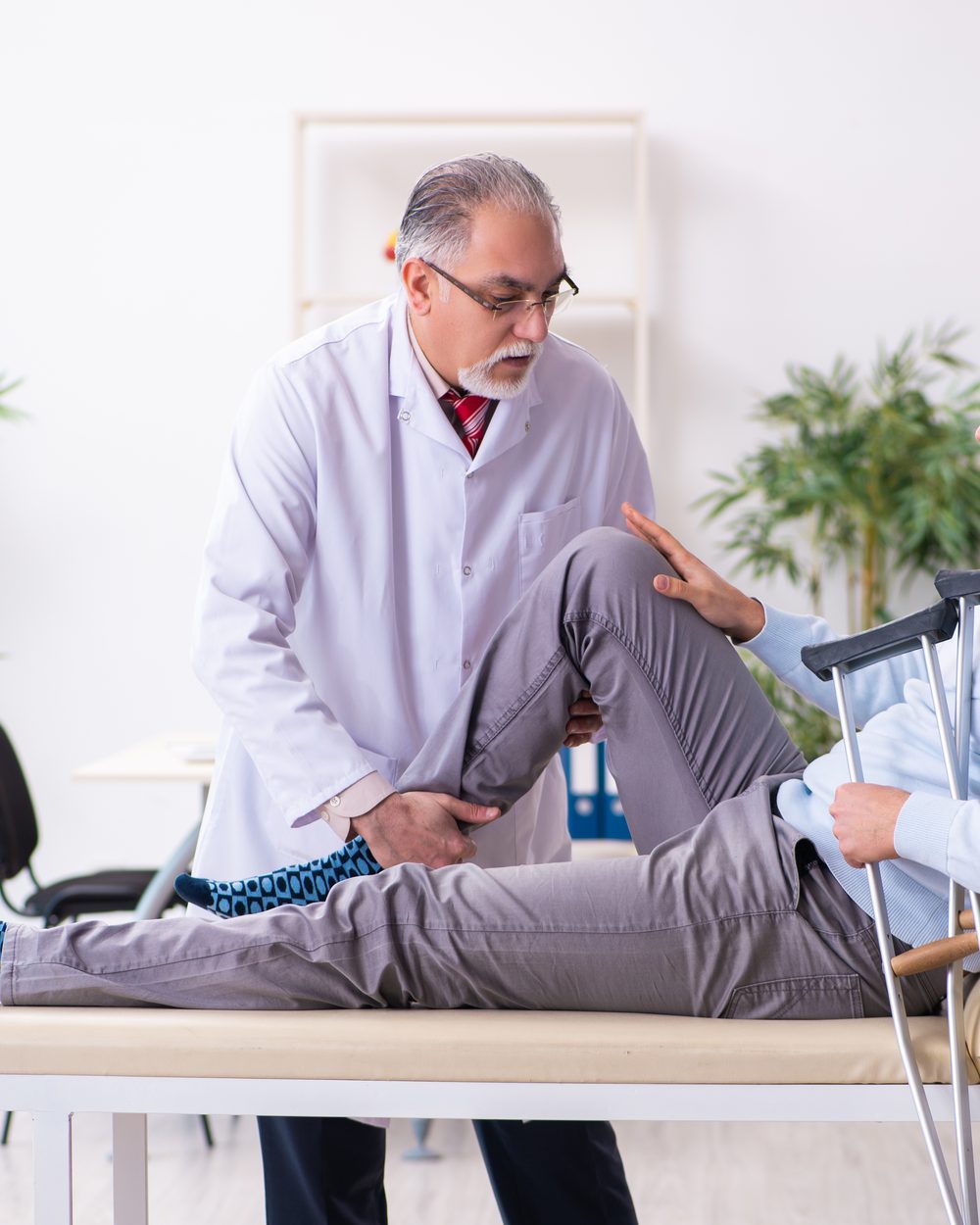 Physician examining an injured patient with crutches during a personal injury evaluation — chiropractic whiplash injury management CE; CCEDseminars category page
