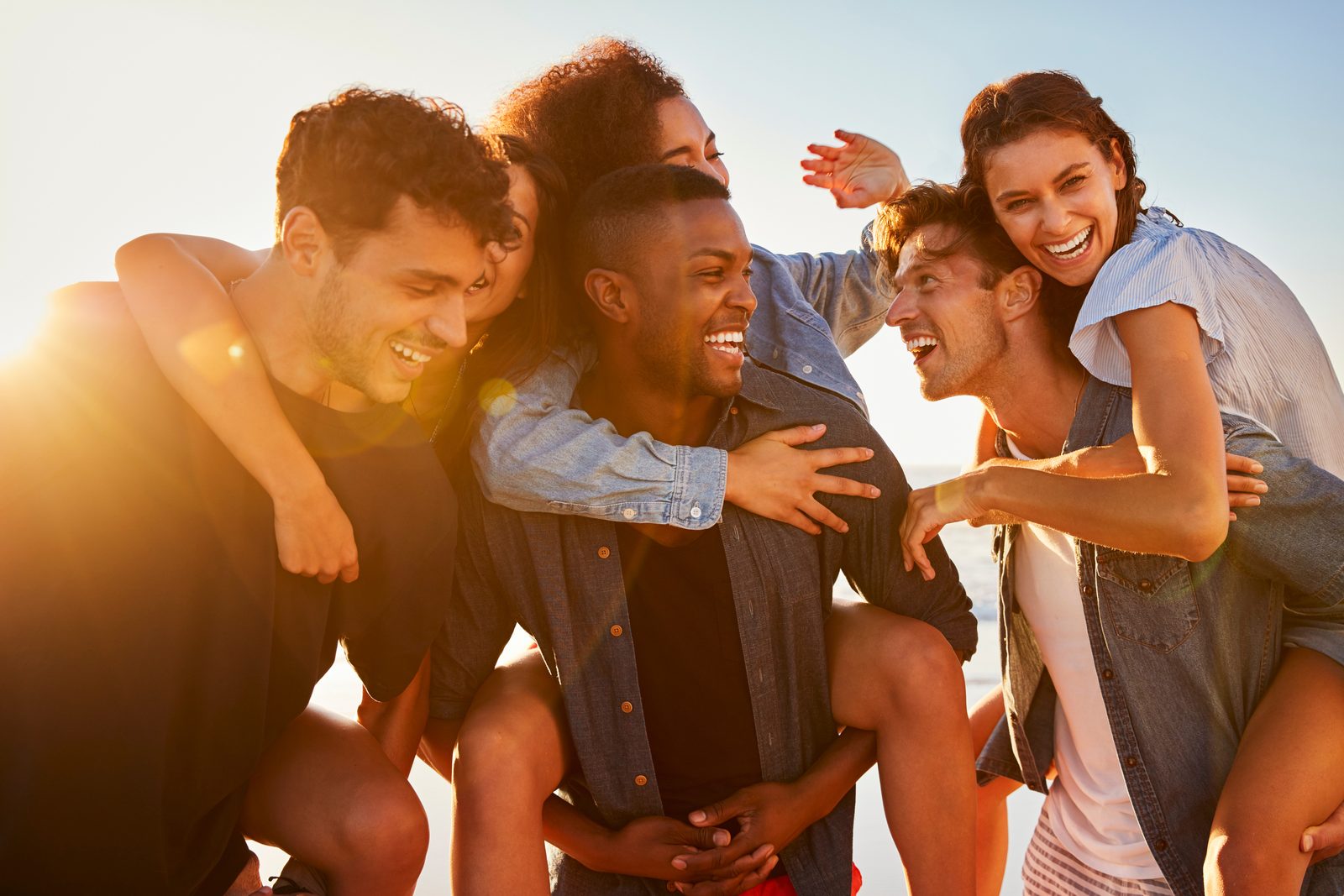 Group of friends laughing together in warm golden sunlight at the beach — Orthopedics 223: Inflammation & Relationships, a 2-hour chiropractic CE course