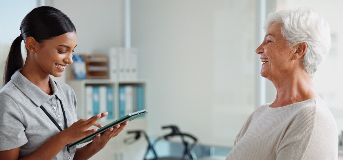 Chiropractic assistant greeting an older patient—CCA online training & certification with live webinars, on-demand modules, instant certificates