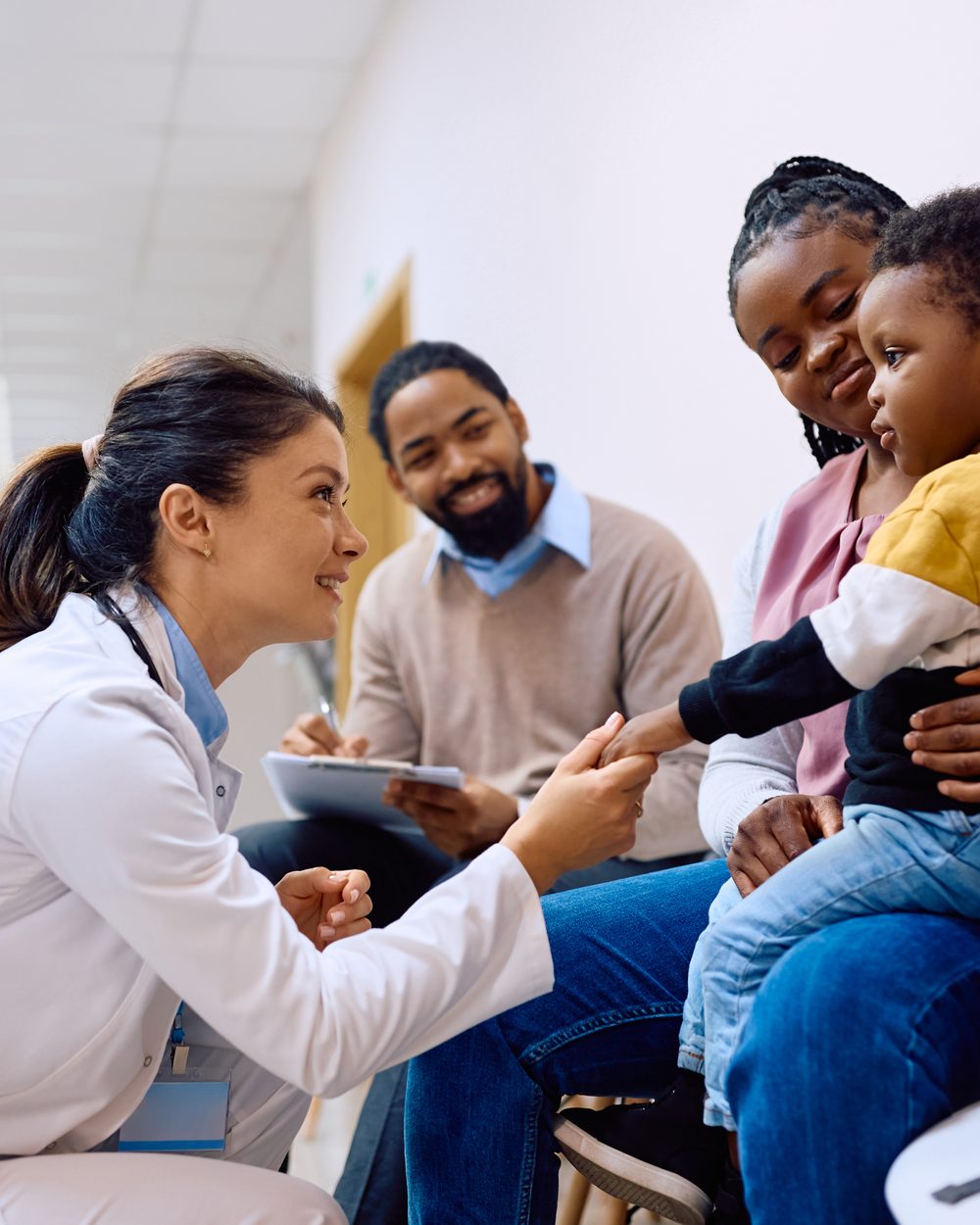 Doctor greeting a young child with parents in a clinic — chiropractic pediatrics CE courses; CCEDseminars category page