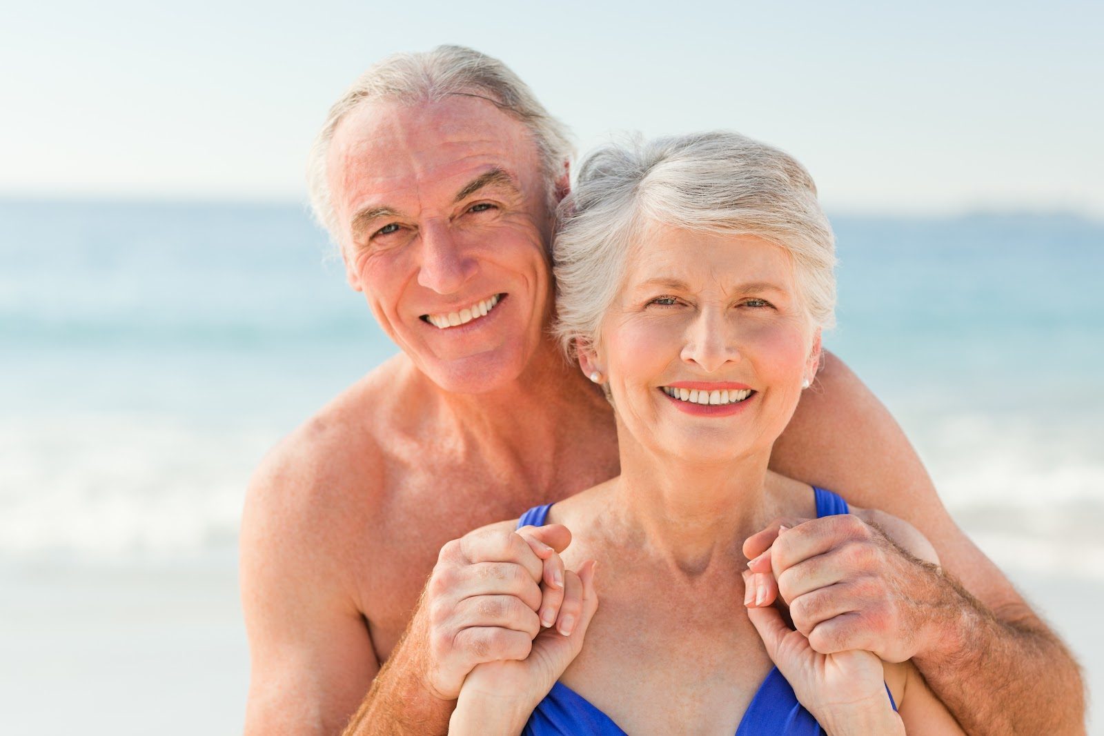 Smiling older couple embracing on a sunny beach