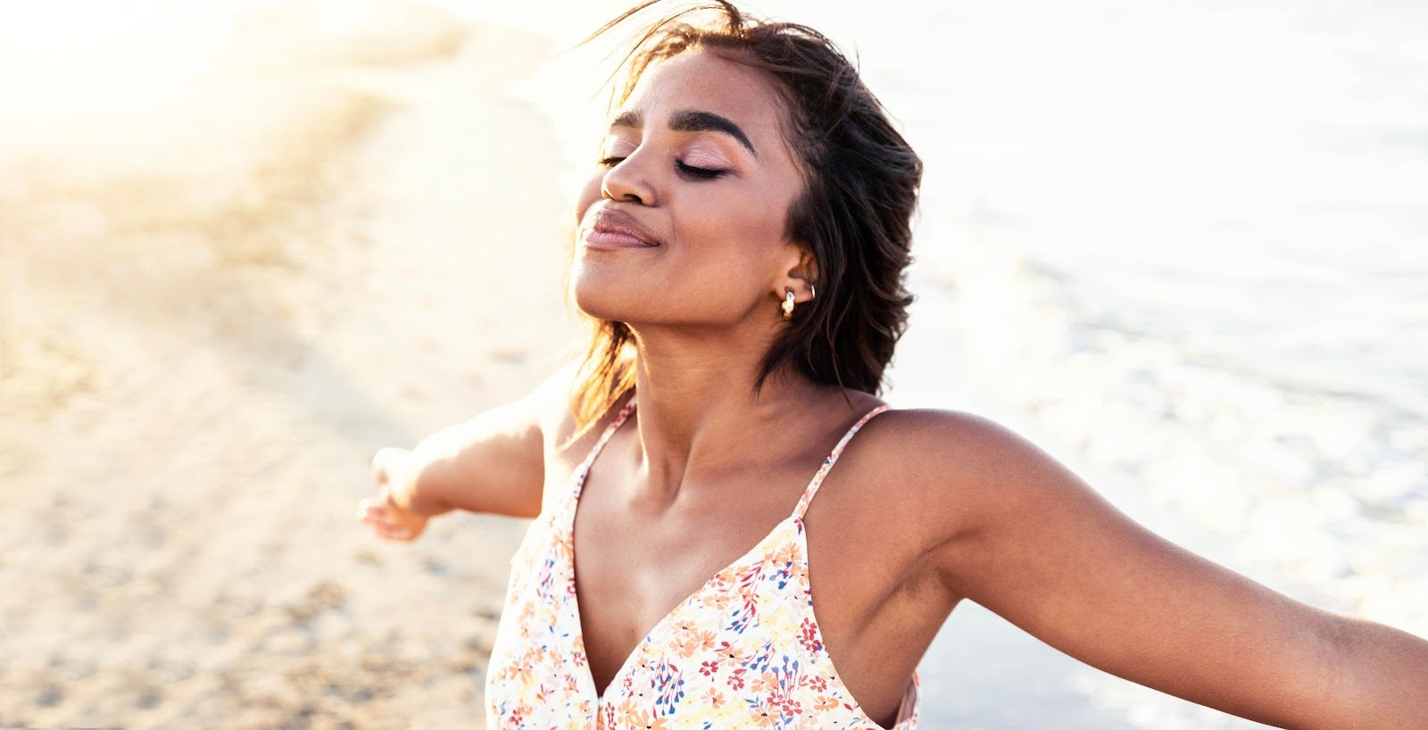 Woman with open arms enjoying fresh air outdoors in the sunshine