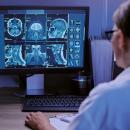 A professional clinical photograph for CCEDseminars' Course 204. A chiropractor's hand points to a high-definition tablet screen displaying 'Evidence Based Practice 204: Imaging in Clinical Practice II' and 'ADVANCED INTERPRETATION & REPORTING.' The screen shows a complex spinal MRI side-by-side with a structured clinical report, reflecting the advanced diagnostic protocols taught by Dr. Monte Horne.