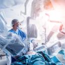 A POV shot from a clinician's perspective. One hand holds a tablet displaying 