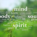 Green word cloud built around the words mind, body, soul and spirit with wellness terms scattered across a leafy background