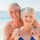 Smiling older couple embracing on a sunny beach